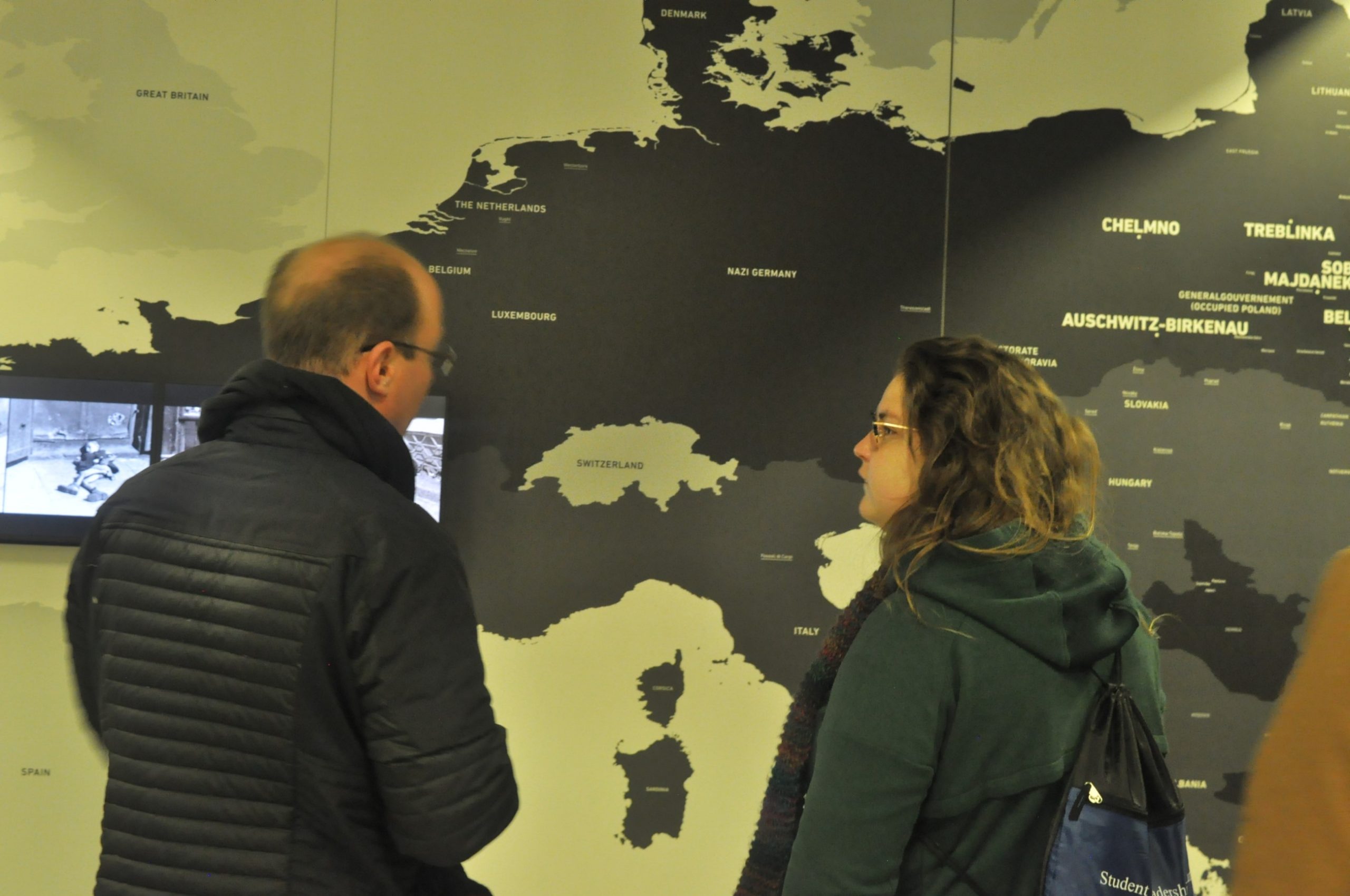 two people stand before a map in the museum side of Auschwitz