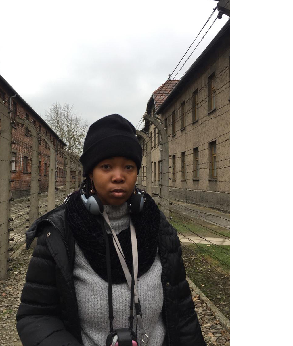 Standing amidst barbed wire and guard towers at Auschwitz I.